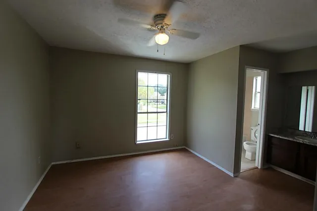 an empty room with windows and ceiling fan