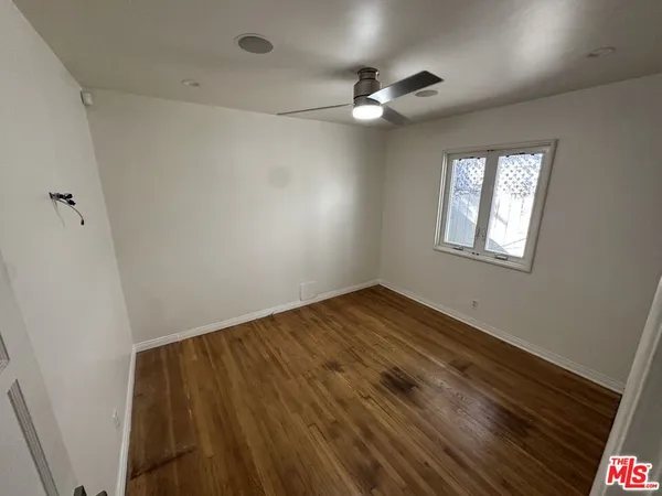 an empty room with wooden floor fan and windows