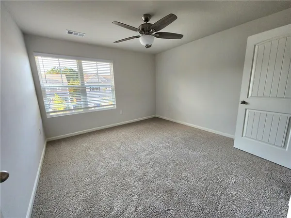 an empty room with a window and a ceiling fan