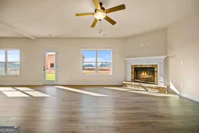 a view of an empty room with window and wooden floor