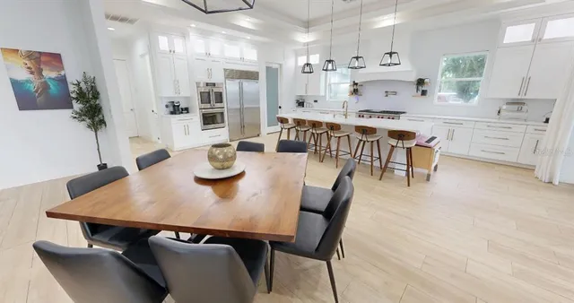 a kitchen with stainless steel appliances kitchen island a table and chairs in it