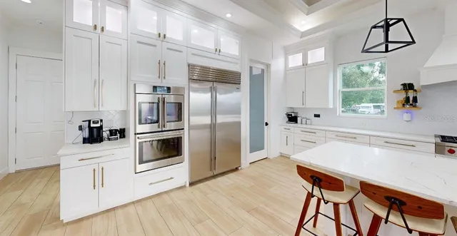 a kitchen with stainless steel appliances a stove a sink and white cabinets