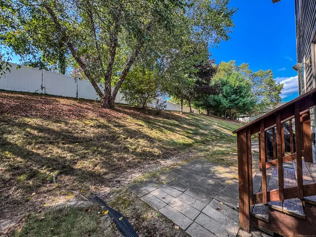 a view of a backyard with wooden fence and large trees