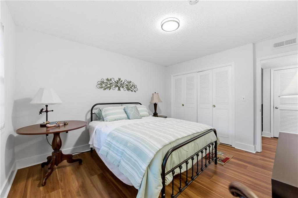 6851 Roswell Road, Unit F15 Atlanta, GA 30328 - Photo 17 of 31 a bedroom with a bed and wooden floor
