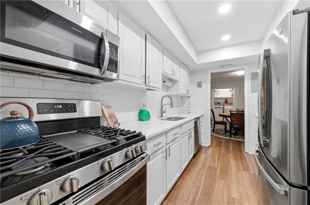 6851 Roswell Road, Unit F15 Atlanta, GA 30328 - Photo 6 of 31 a kitchen with stainless steel appliances kitchen island granite countertop a stove and a sink