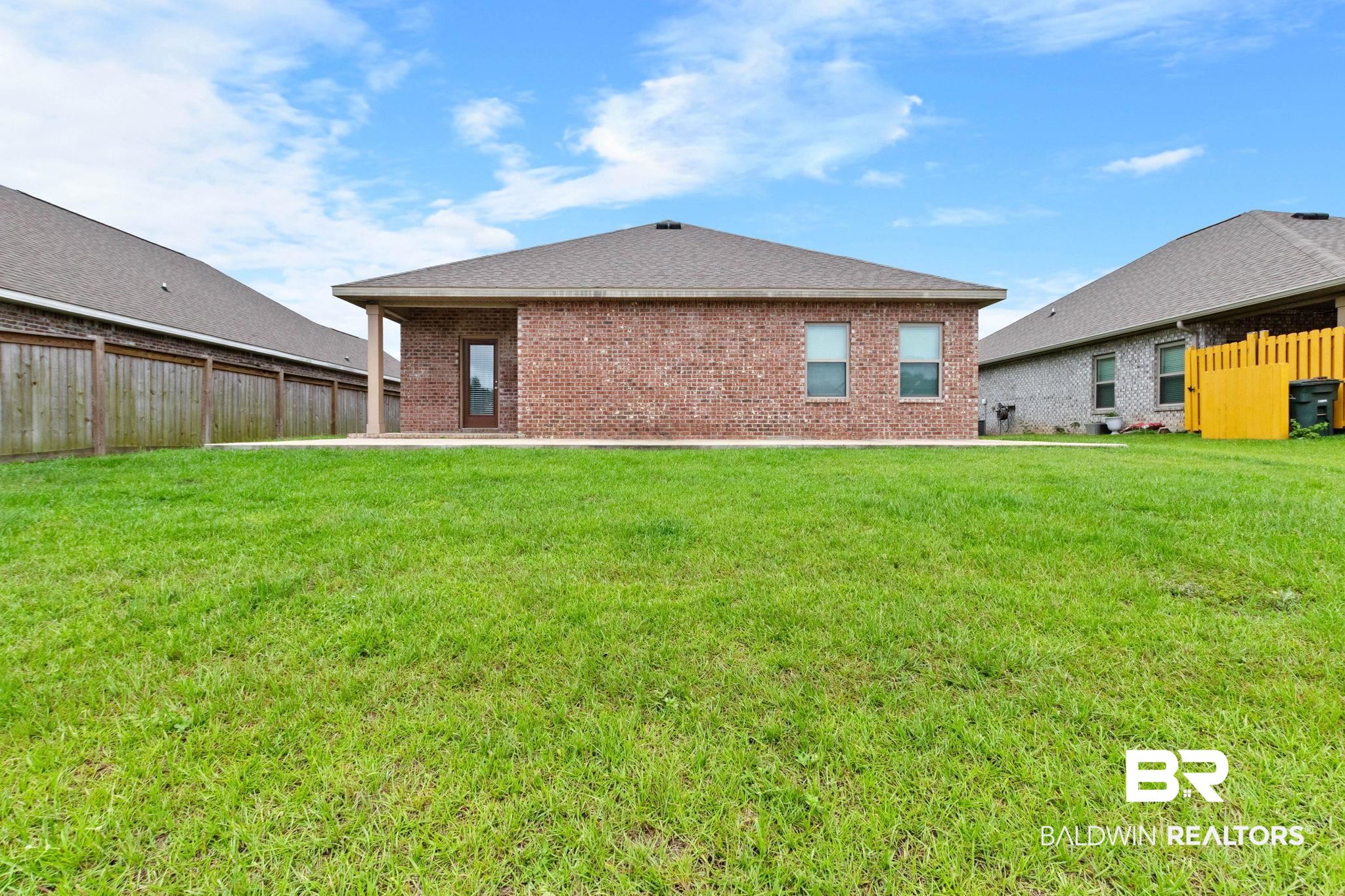 1710 Grouse Street Foley, AL 36535 - Photo 60 of 76 Expansive backyard featuring a manicured lawn, full brick exterior, covered patio, and privacy fencing