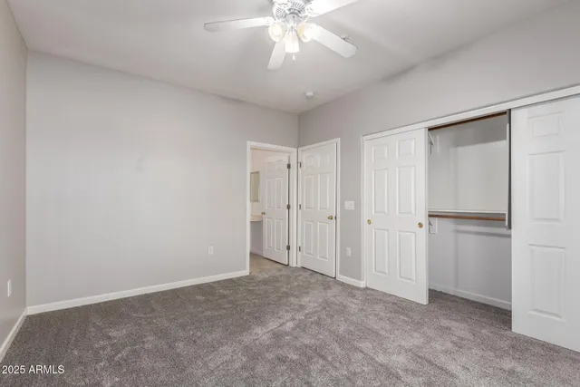 an empty room with closet and a ceiling fan
