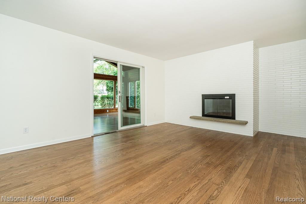 144 West Maryknoll Road Rochester, MI 48309 - Photo 20 of 38 Spacious living area featuring warm wood-finish flooring, white walls, and abundant natural light from glass sliding doors opening to outdoor space