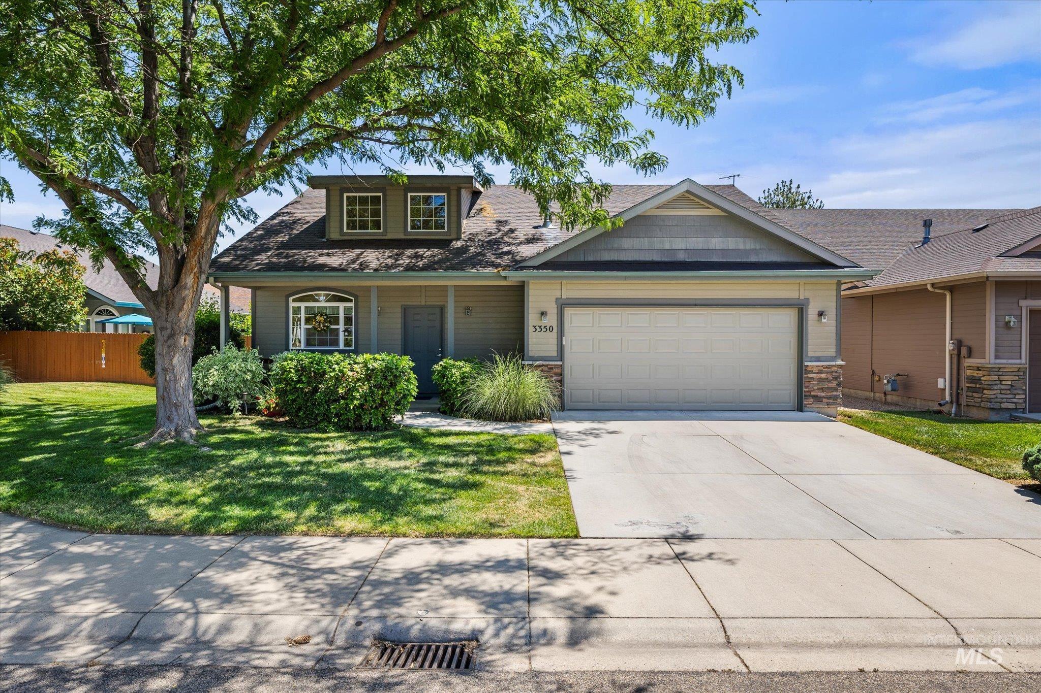 View of front of house featuring an attached garage, driveway, stone siding, and covered porch