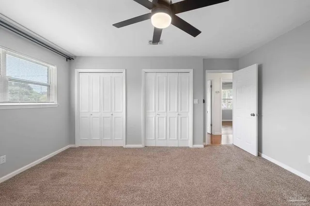 a view of an empty room and chandelier fan