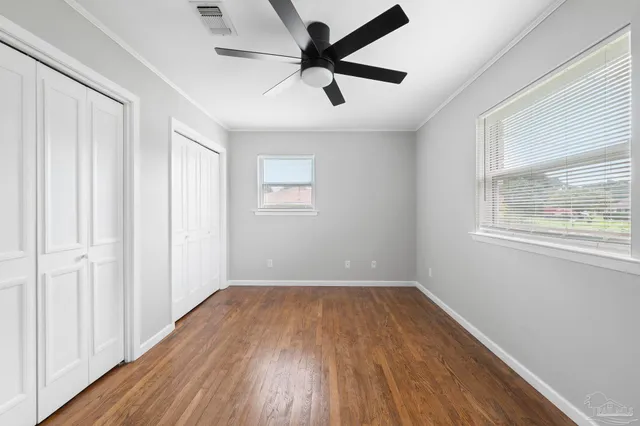 a view of empty room with wooden floor and fan