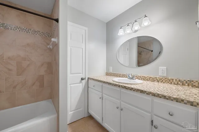 a bathroom with a granite countertop sink mirror and a bathtub