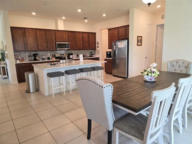 a kitchen with stainless steel appliances granite countertop a refrigerator a stove a sink a dining table and chairs