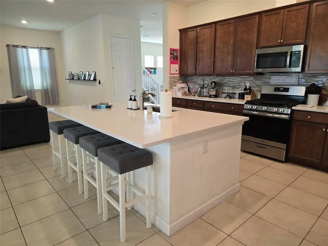 a kitchen with stainless steel appliances a stove a sink a microwave a refrigerator and cabinets