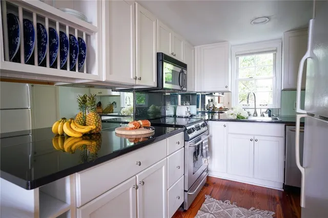 a bathroom with a granite countertop sink a toilet and a window