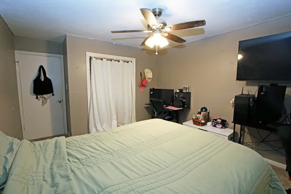 a bedroom with a bed and a flat tv screen on a dresser