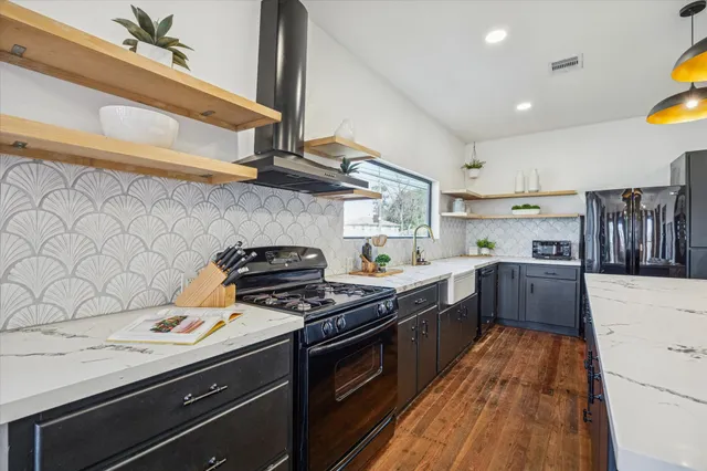 a kitchen with stainless steel appliances granite countertop a sink a stove and a wooden floors