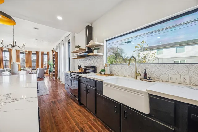 a large kitchen with stainless steel appliances kitchen island granite countertop a stove a sink dishwasher and white cabinets with wooden floor