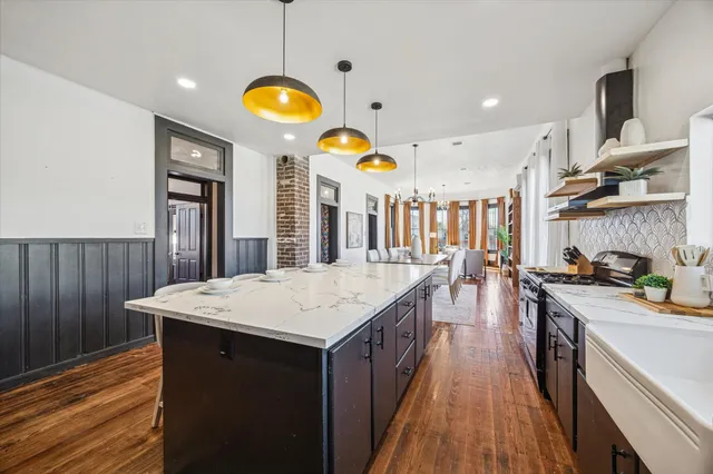 a kitchen with stainless steel appliances granite countertop a dining table chairs and wooden floor