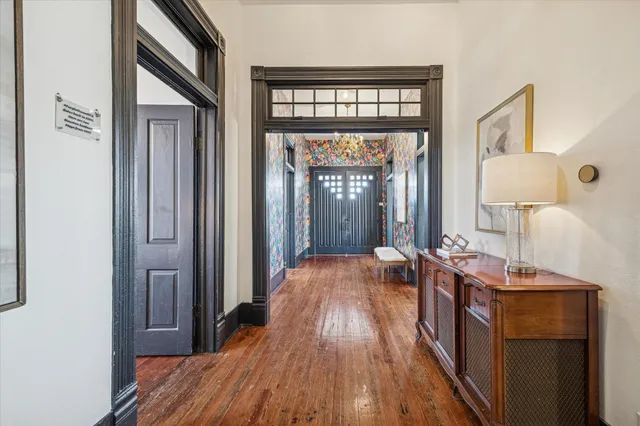 a view of a dining room and livingroom with furniture wooden floor a rug a painting and a chandelier