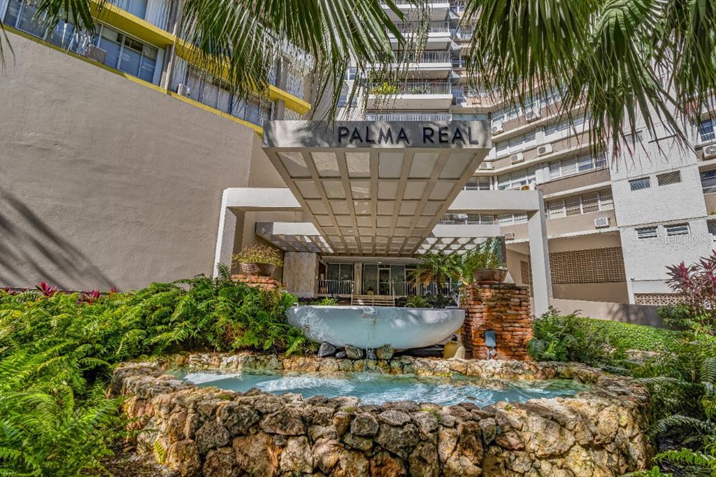 a view of a backyard with a fountain plants and large tree