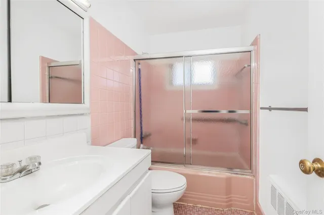 a bathroom with a bathtub shower sink vanity and toilet