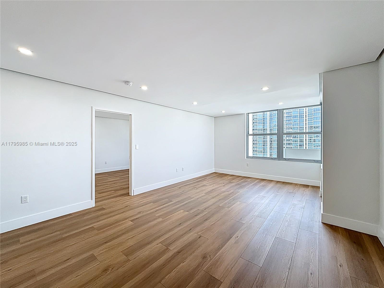 2899 Collins Avenue, Unit 1218 Miami Beach, FL 33140 - Photo 14 of 41 a view of an empty room with wooden floor and a window