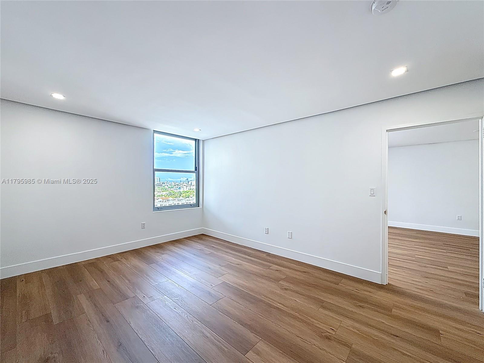 2899 Collins Avenue, Unit 1218 Miami Beach, FL 33140 - Photo 21 of 41 an empty room with wooden floor and windows