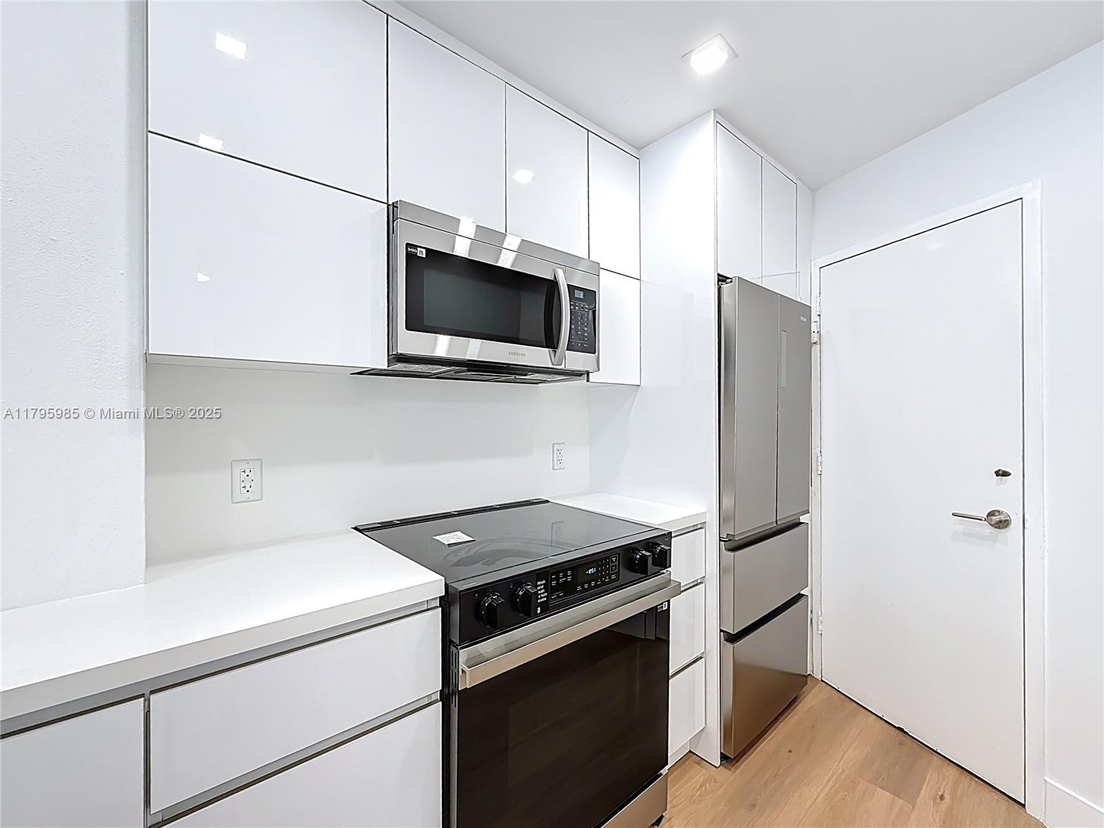 2899 Collins Avenue, Unit 1218 Miami Beach, FL 33140 - Photo 10 of 41 a kitchen with stainless steel appliances a stove a microwave and a refrigerator