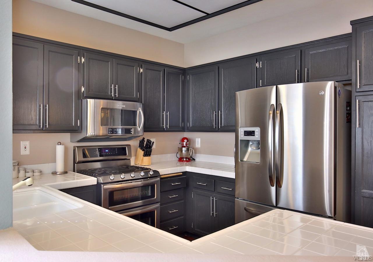 4241 Rusticview Court Moorpark, CA 93021 - Photo 11 of 26 a kitchen with stainless steel appliances granite countertop a refrigerator stove a sink dishwasher and wooden cabinets