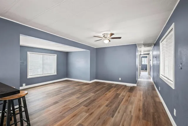 a view of an empty room with a window and wooden floor