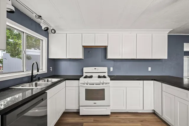 a kitchen with granite countertop white cabinets and white appliances