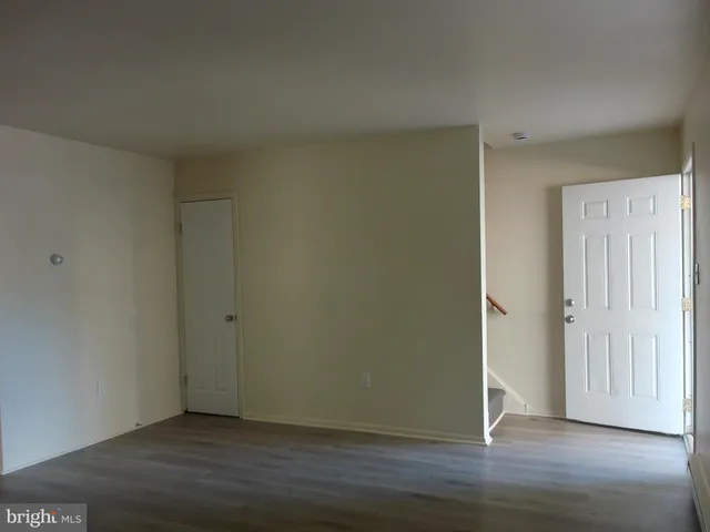 a view of an empty room with wooden floor and closet