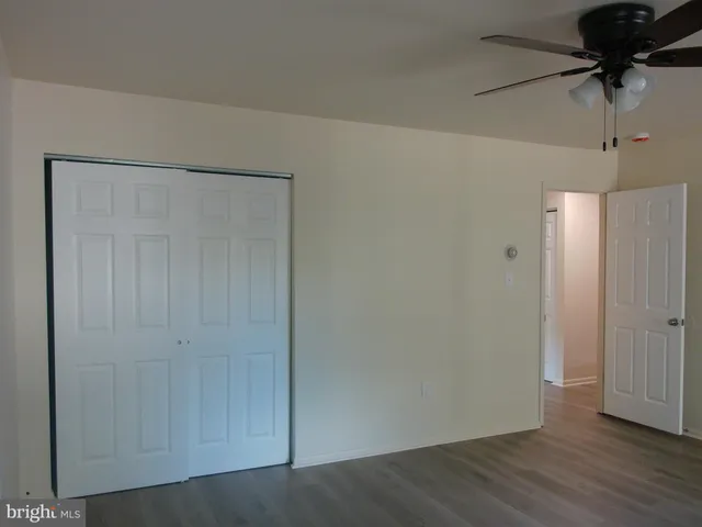 an empty room with wooden floor windows and fan