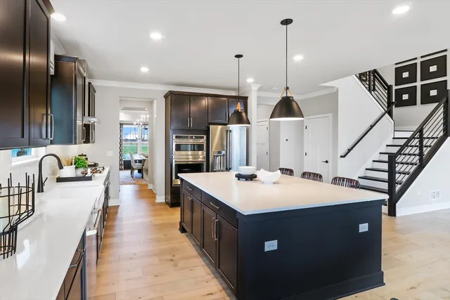 a large kitchen with kitchen island a stove a sink a refrigerator and a dining table with wooden floor