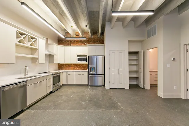 a large white kitchen with cabinets a sink and stainless steel appliances