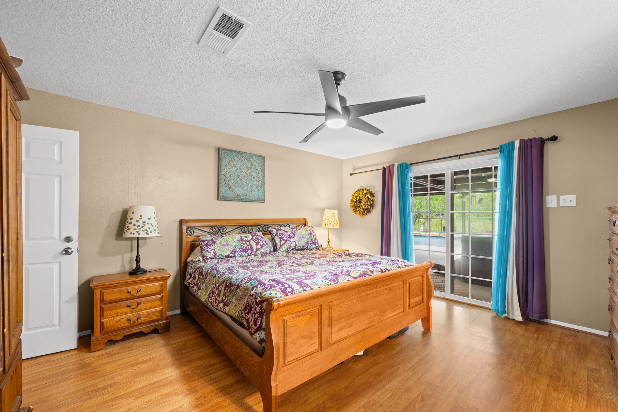 15602 Fir Road Santa Fe, TX 77517 - Photo 16 of 42 Spacious primary bedroom featuring warm wood-look flooring, a modern ceiling fan, and abundant natural light. Sliding glass doors provide easy access to the outdoor living area while enhancing the room’s bright and airy feel.