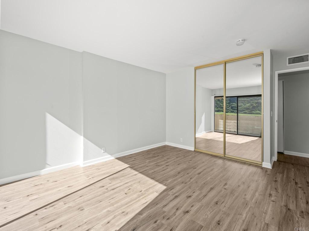 2639 Pirineos Way, Unit 231 Carlsbad, CA 92009 - Photo 13 of 34 a view of an empty room with wooden floor and a window