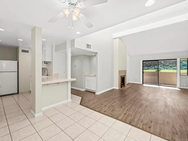 a open kitchen with kitchen island granite countertop a refrigerator and white cabinets