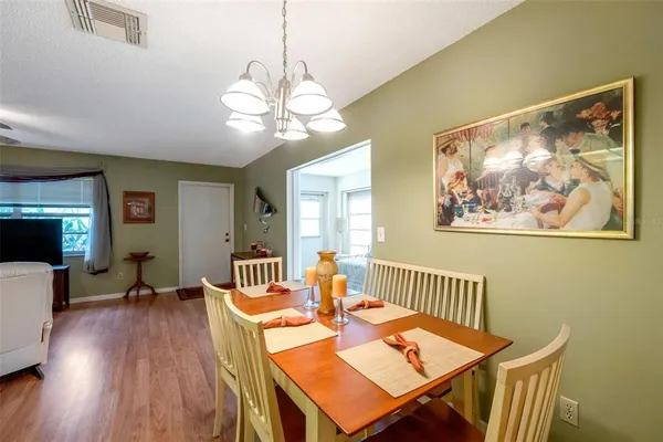 a view of a dining room with furniture a chandelier and wooden floor