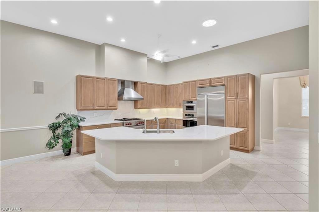 6676 Glen Arbor Way Naples, FL 34119 - Photo 11 of 23 a view of a kitchen with kitchen island stainless steel appliances a sink a stove and a refrigerator