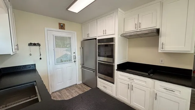 a kitchen with granite countertop white cabinets and white appliances
