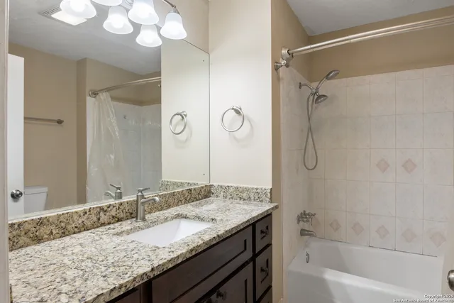 a bathroom with a granite countertop sink a mirror and a bathtub