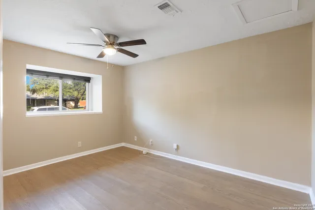 an empty room with a window and a fan