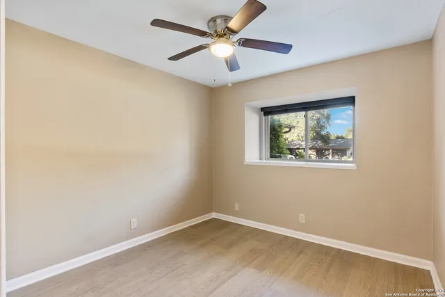 an empty room with a window and a ceiling fan