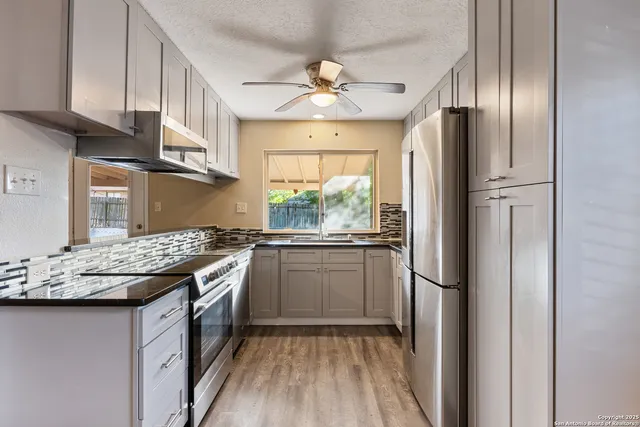 a kitchen with stainless steel appliances granite countertop a refrigerator a sink dishwasher a stove and white countertops with wooden floor