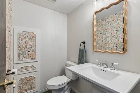 a bathroom with a sink mirror and a toilet