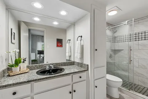 a bathroom with a granite countertop sink a toilet and shower