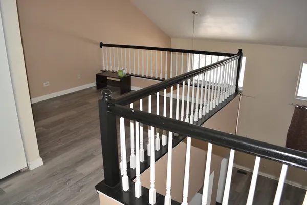 a view of staircase with railing and white walls