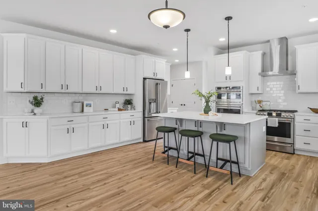 a kitchen with stainless steel appliances granite countertop a stove a sink dishwasher and a refrigerator with white cabinets